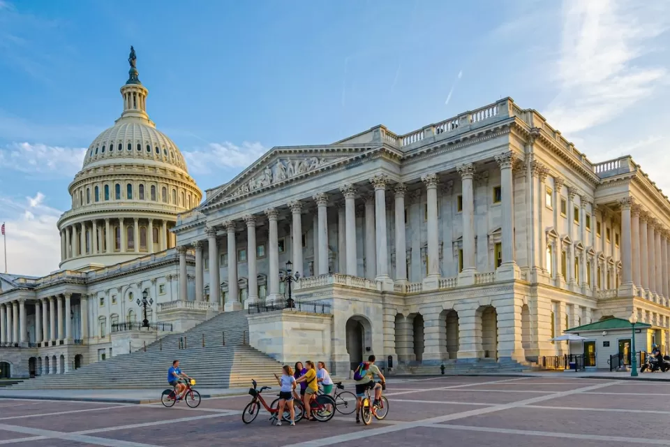 Wide shot of group of people with bikes standing in plaza near U.S. Capitol in Washington, D.C.